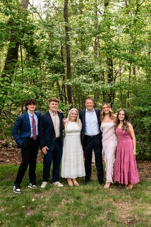 Outdoor group photo in wooded setting wearing coordinated formal attire.