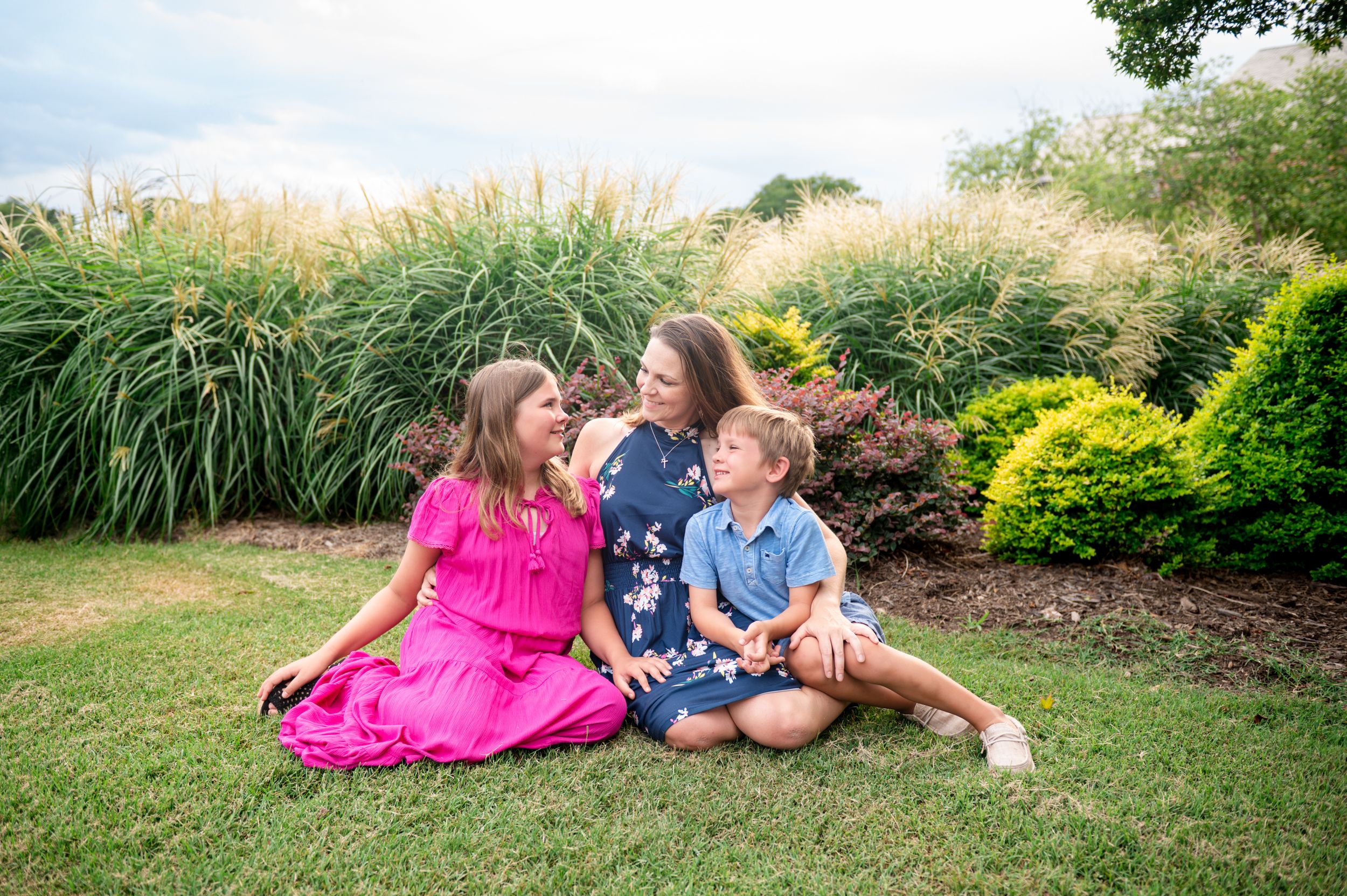 Relaxed family photoshoot in a garden setting with natural sunlight filtering through.