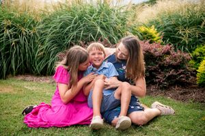 Candid family portrait against ornamental grasses and landscaping during sunset.