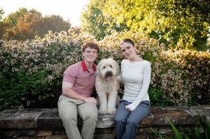 Family members and their large white dog relaxing on outdoor brick patio.