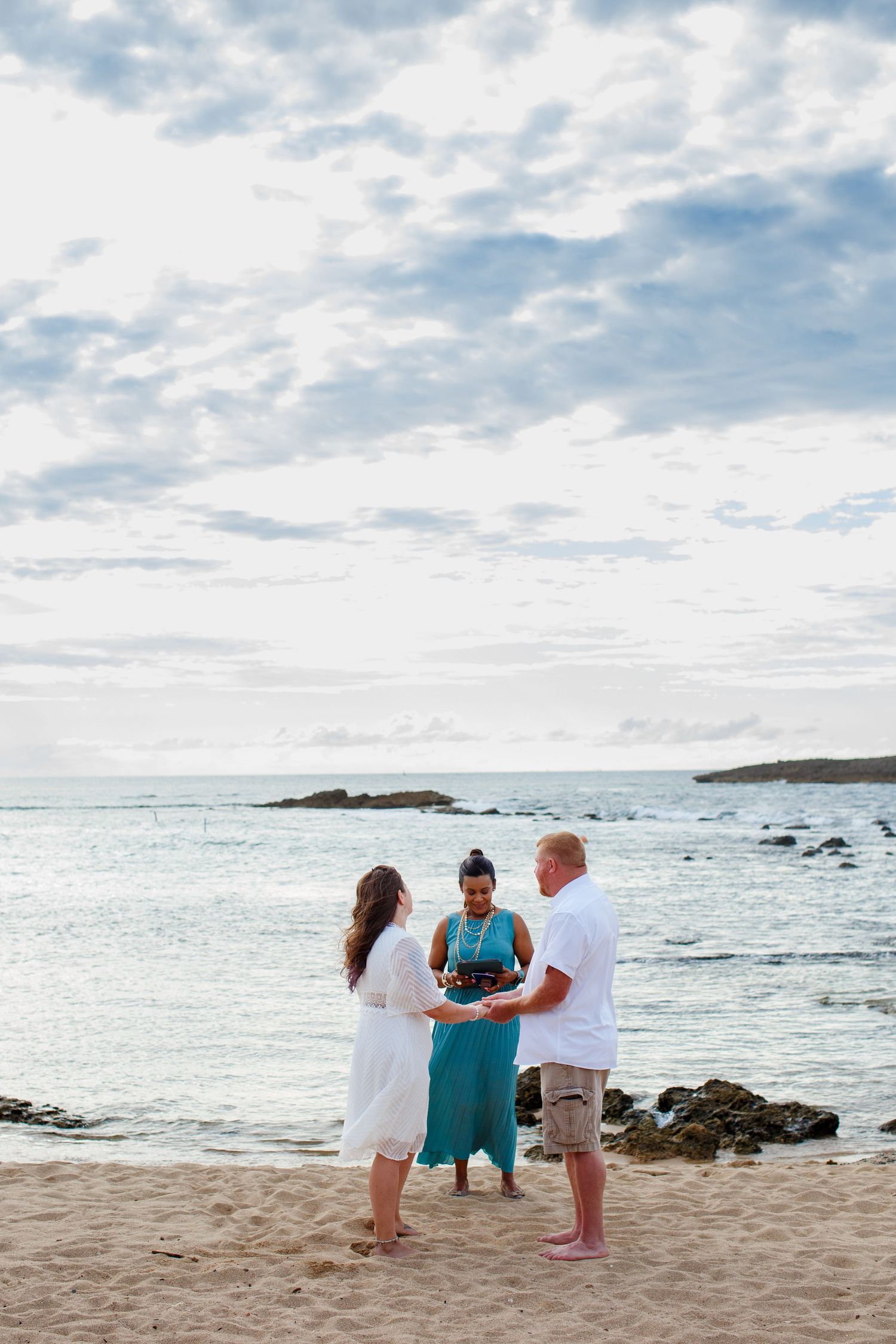 Elopement on the beach at Balneario del Escambrón in Old San Juan, Puerto Rico. Wedding ceremony. Bride, groom, and officiant.