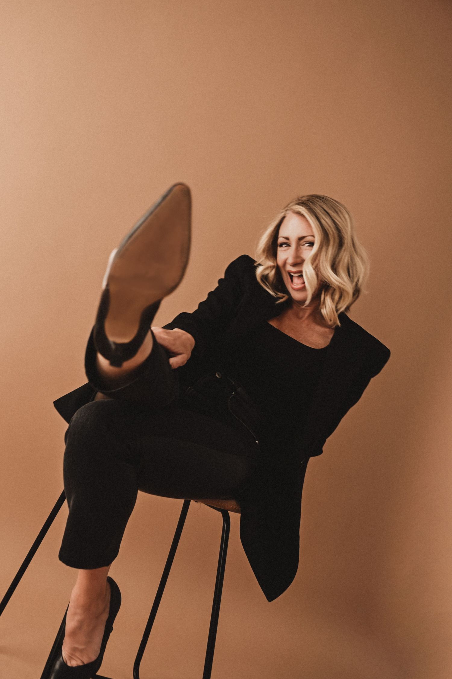 Artistic fashion photo series of person in black outfit posing on chair against brown background.