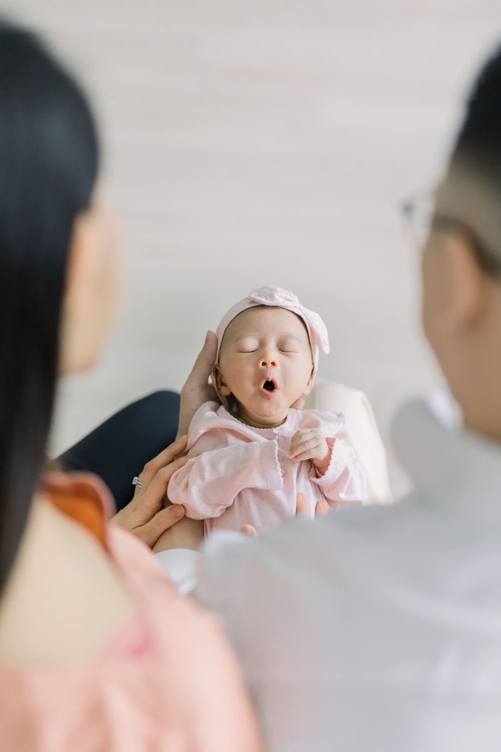 A series of photos showing a baby in pink clothing being held against a light background.