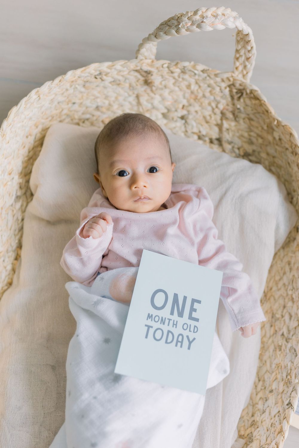 Baby milestone photo series showing growth progression with cards marking age from newborn to one month old.
