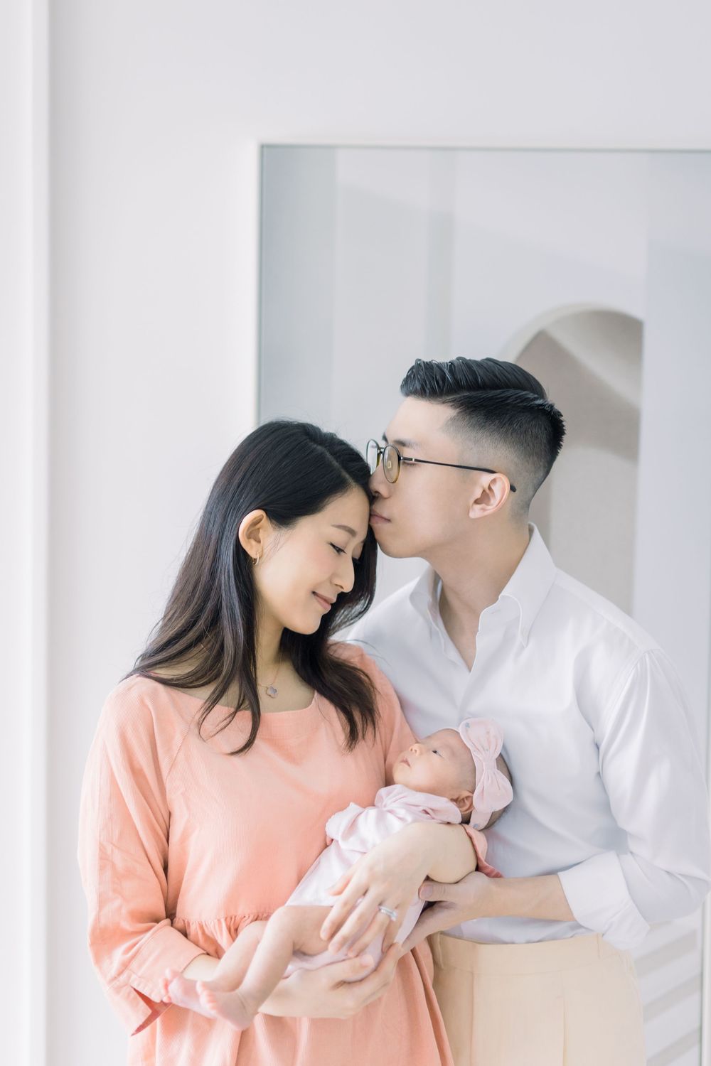 A tender family moment captured in a series of minimalist portraits with soft lighting and pastel colors.