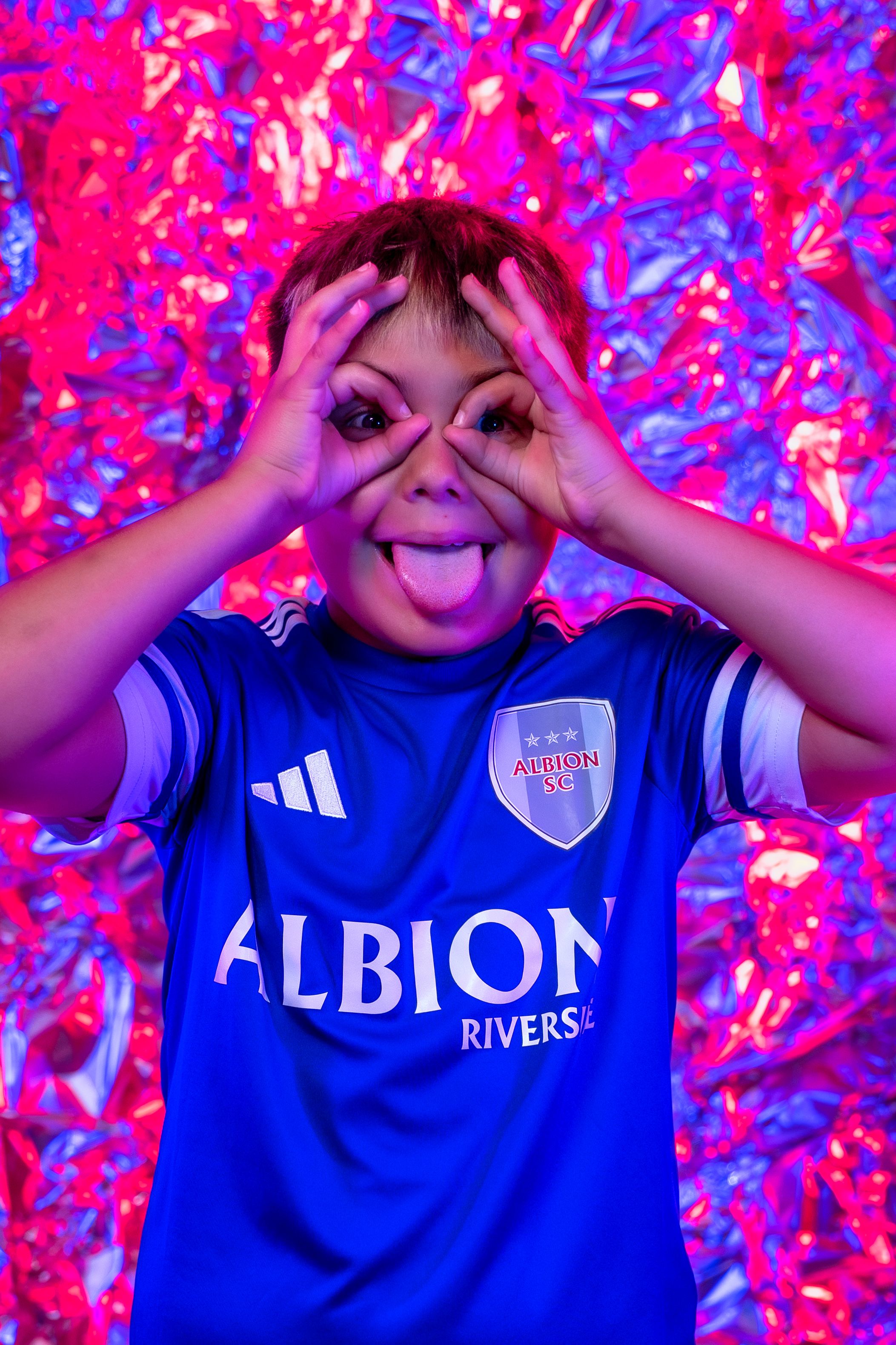 Blue sports jersey with Albion text against vibrant pink and purple abstract background.