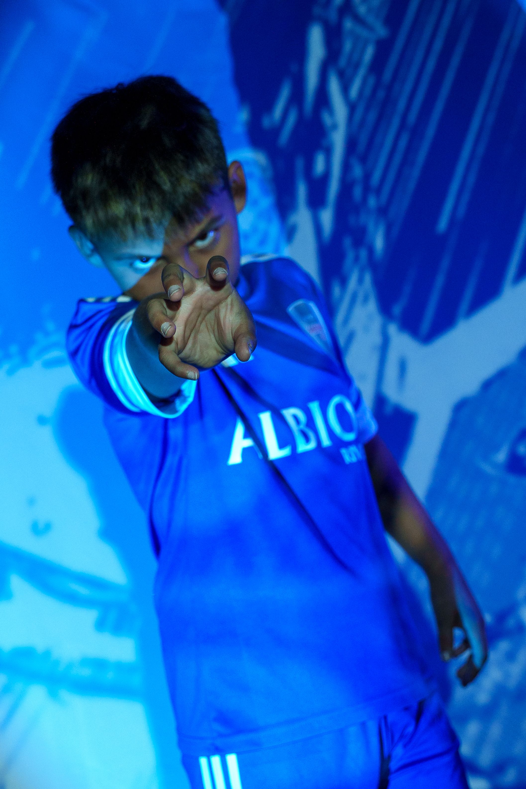 Person in blue Albion jersey photographed under dramatic blue lighting effects.