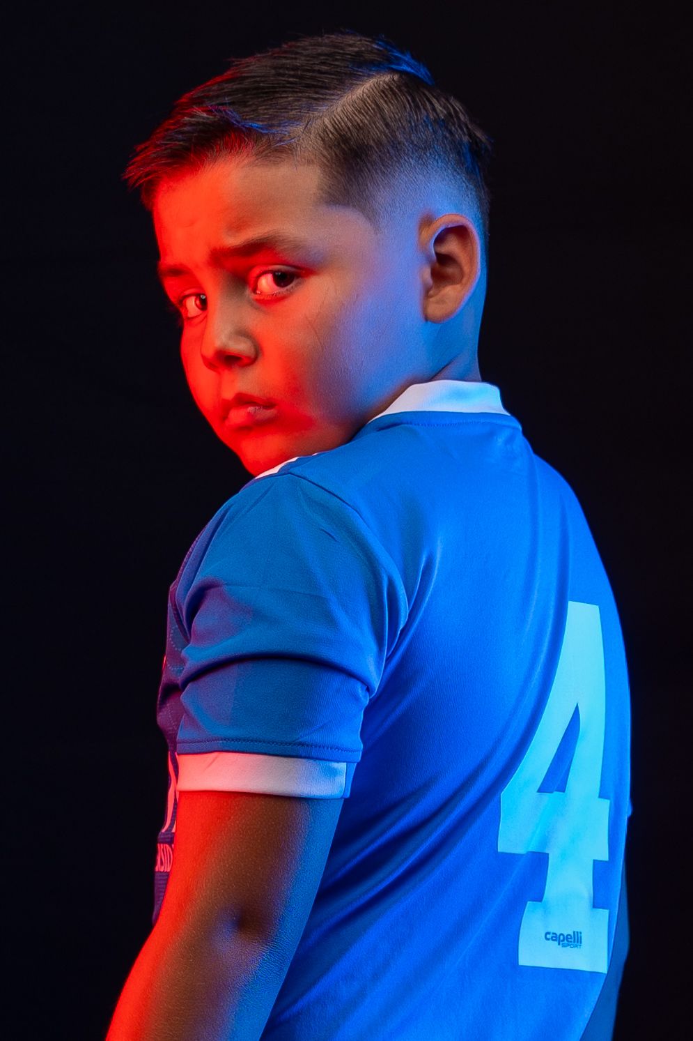 Soccer jersey number 4 highlighted with red and blue dramatic lighting.