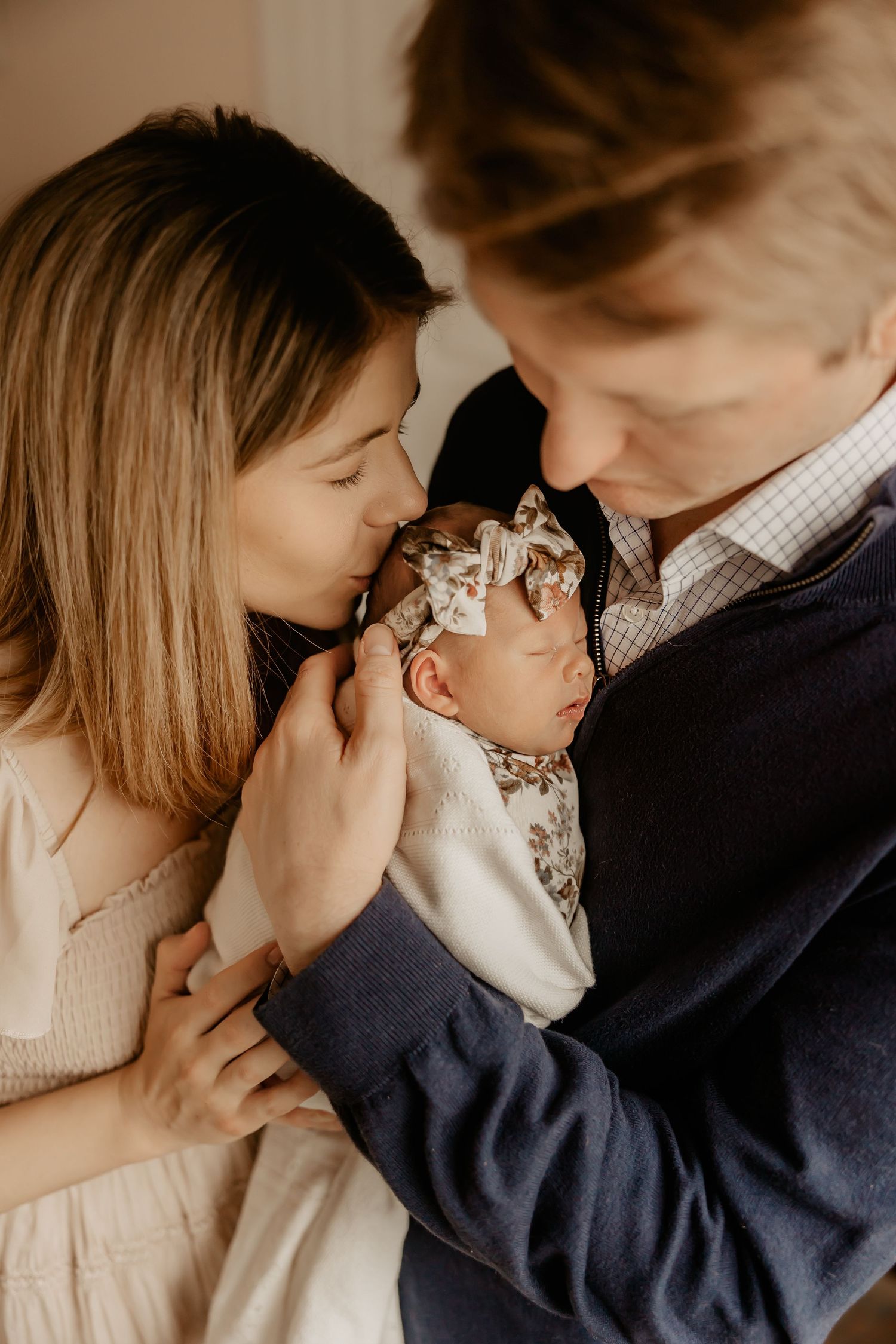 Parents snuggle their newborn baby girl as a Honolulu Newborn Photographer photographs their newborn session.