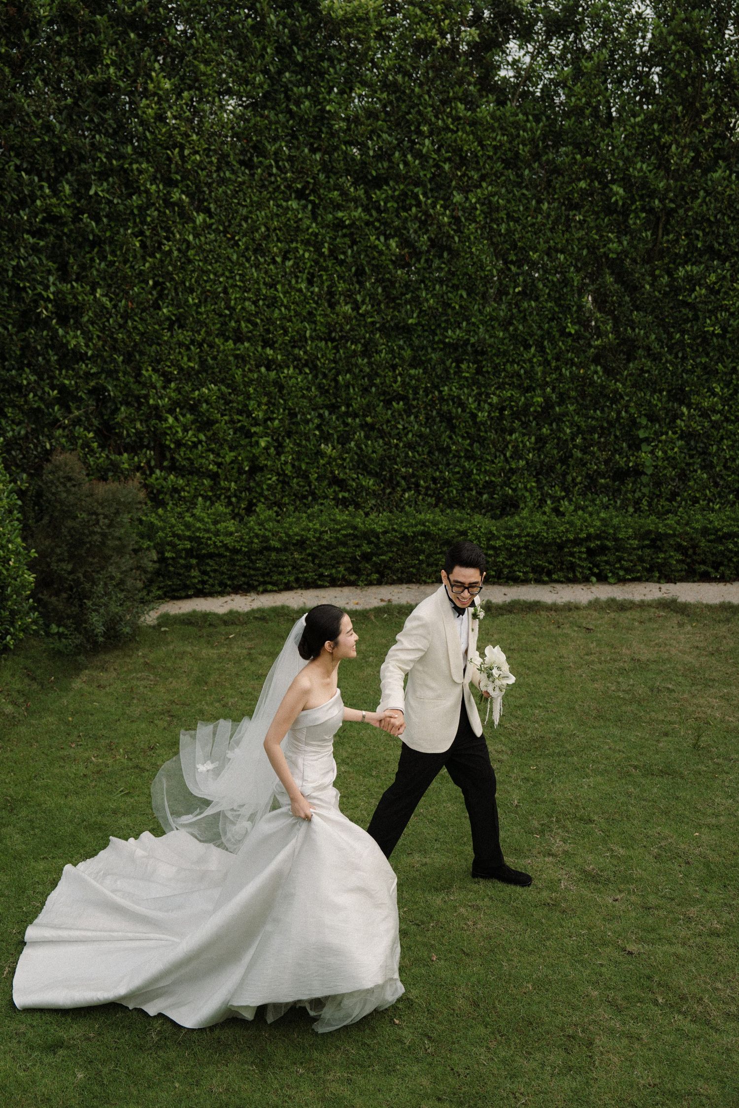 Sequence showing bride's dress flowing dramatically during outdoor wedding photos on grass.