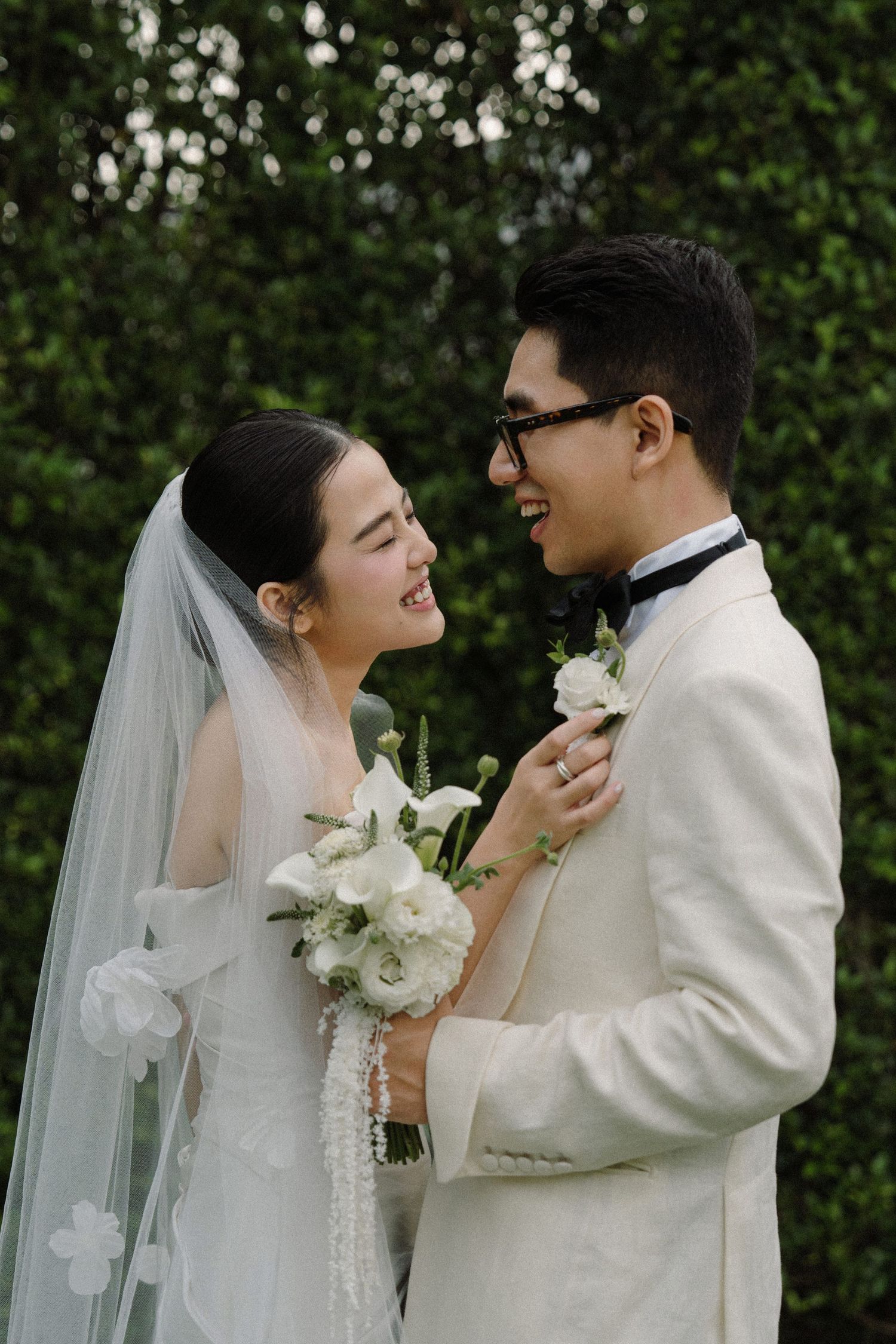 Newlyweds share an intimate moment with white flowers during their garden wedding photoshoot.