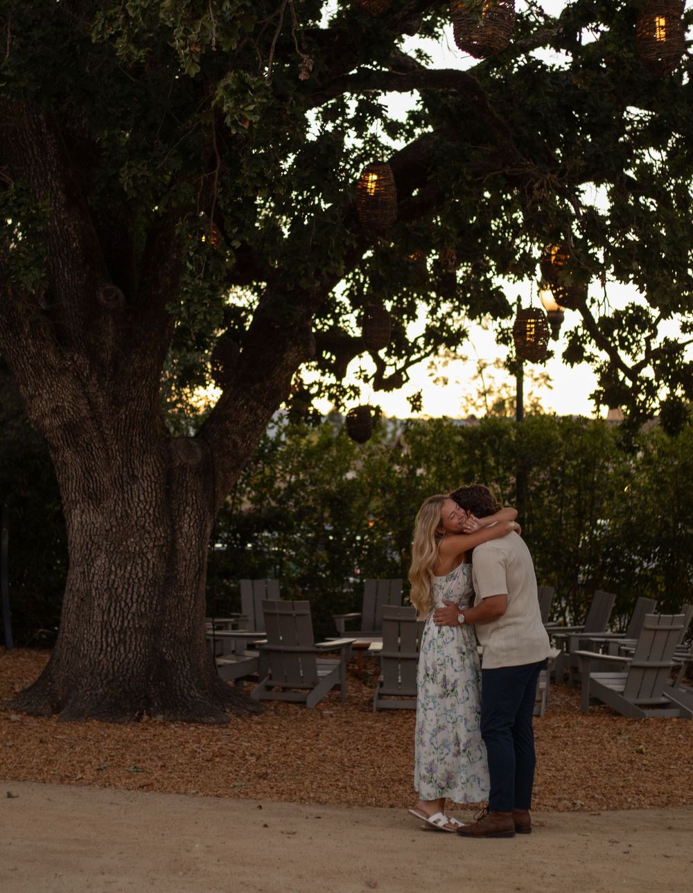 A beautiful moment captured beneath a large tree during golden hour with soft lighting creating a romantic atmosphere.