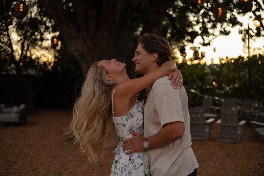 Two people share an intimate dance outdoors at sunset in a romantic garden setting.