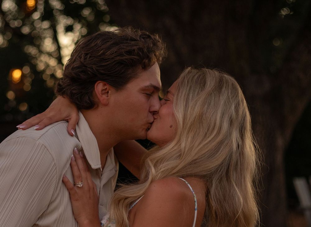Two people sharing a tender moment in a romantic outdoor setting at sunset.