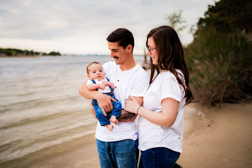 A family enjoying quality time together on a sandy beach by the water on a sunny day.