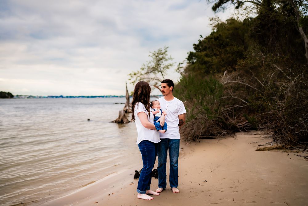 Couple enjoying a romantic afternoon together on a sandy beach with driftwood and cloudy skies.