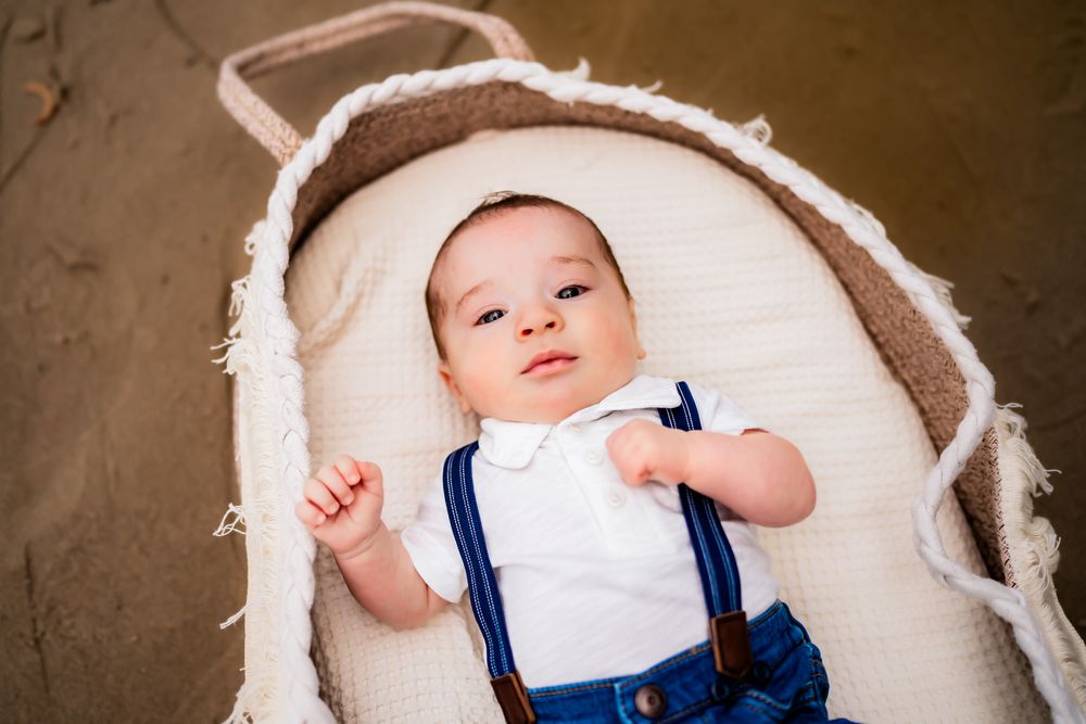 Newborn baby lying down wearing white and blue outfit during a professional photography session.