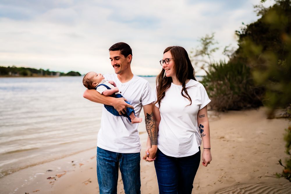 Family members walk together on a sandy beach wearing coordinated white shirts and jeans.