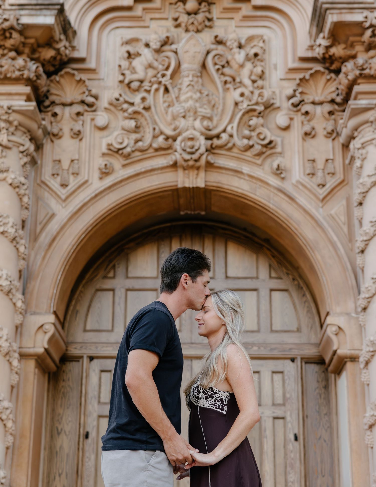 Two people sharing a close moment in front of an ornate Baroque church facade.