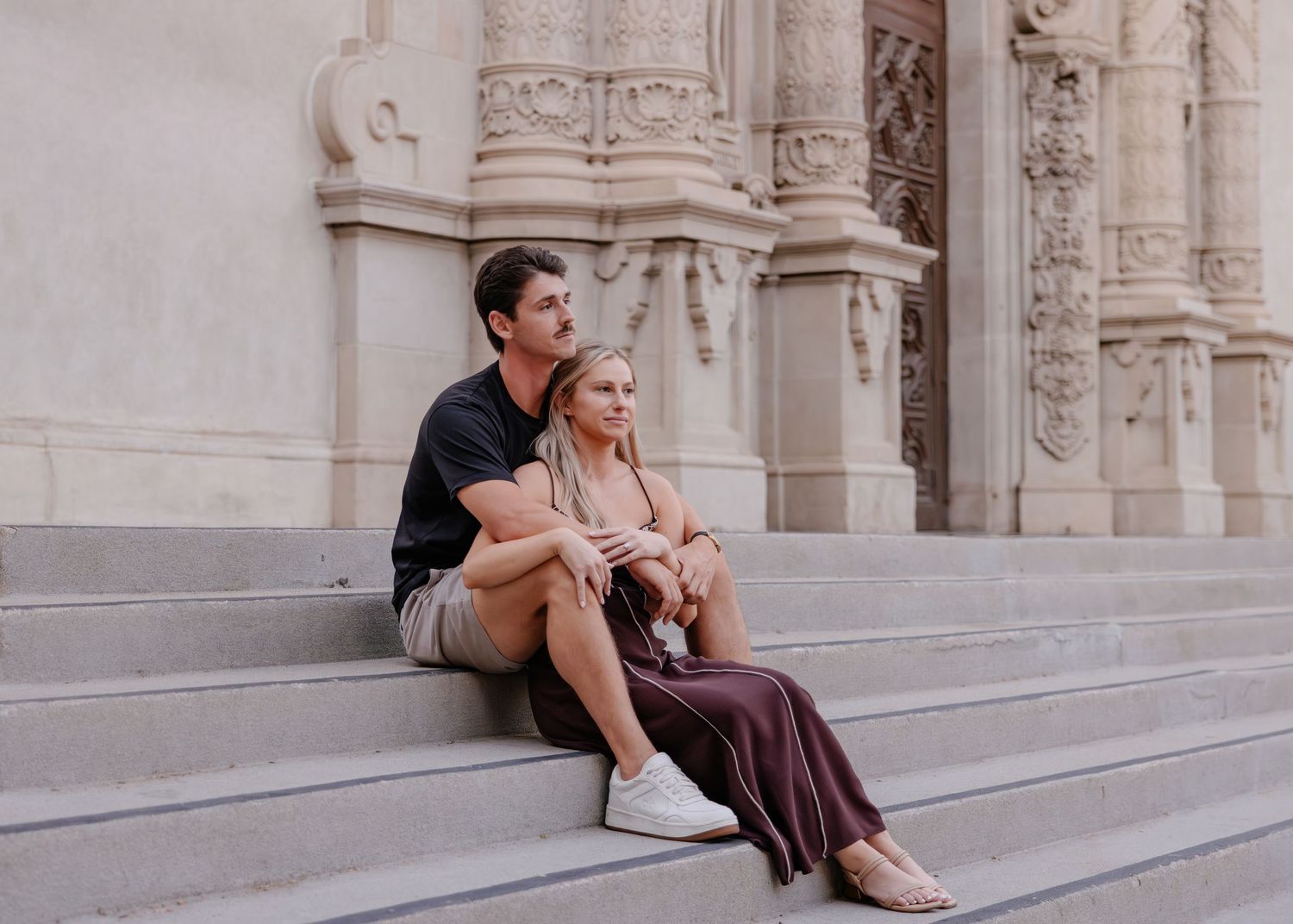People sitting and relaxing on stone steps of a grand historic building.