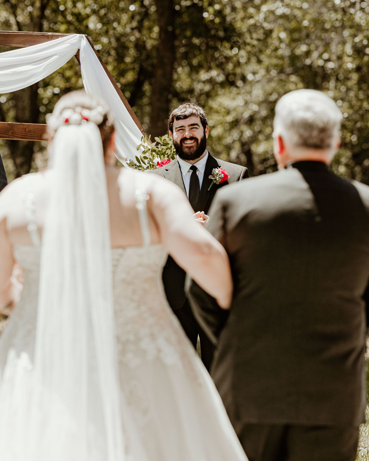 A joyous outdoor wedding ceremony moment features the couple during their vows under white fabric draping. Florida wedding photographer