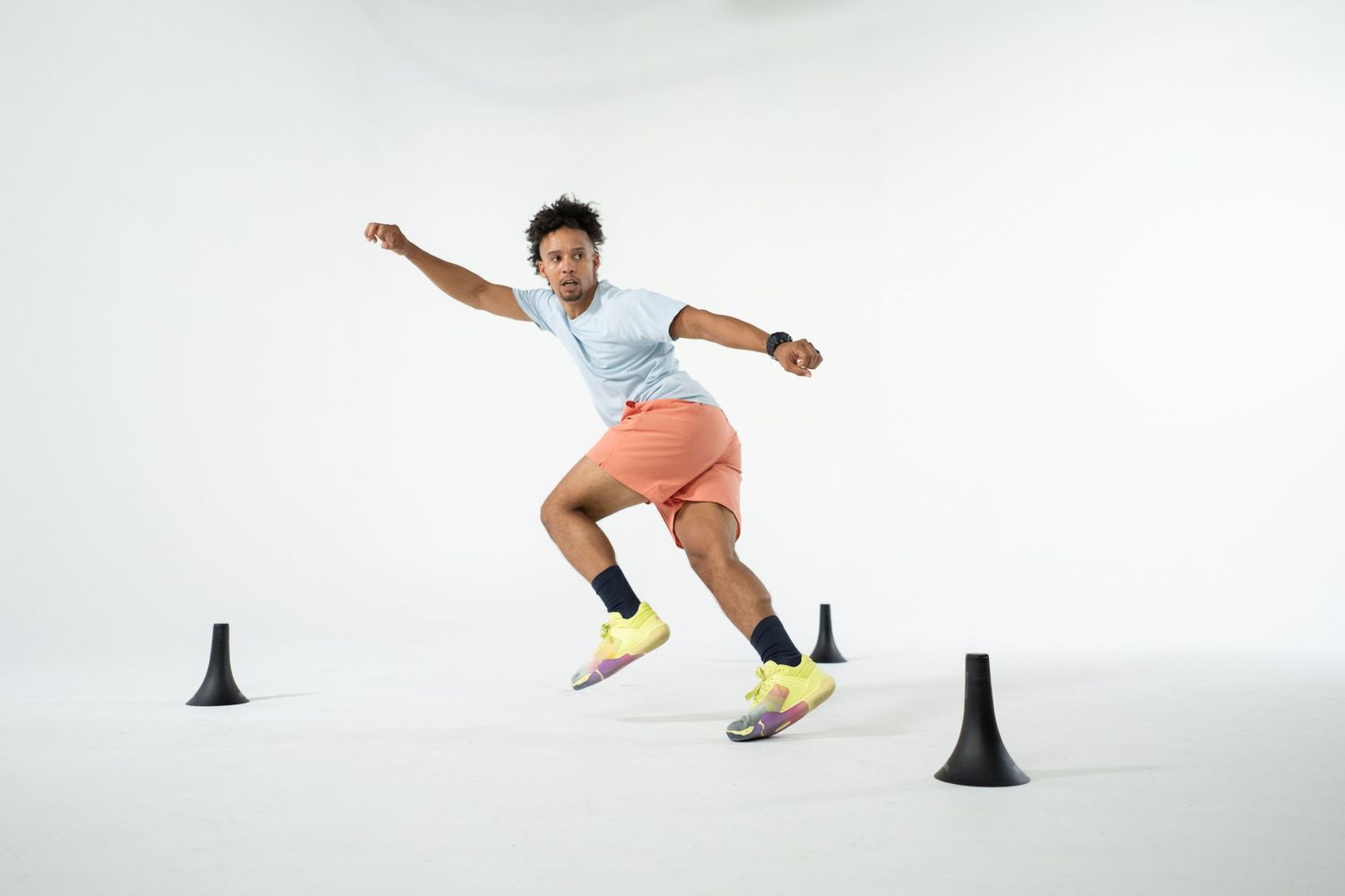 Athlete performs speed and agility drills around training cones on a white background.