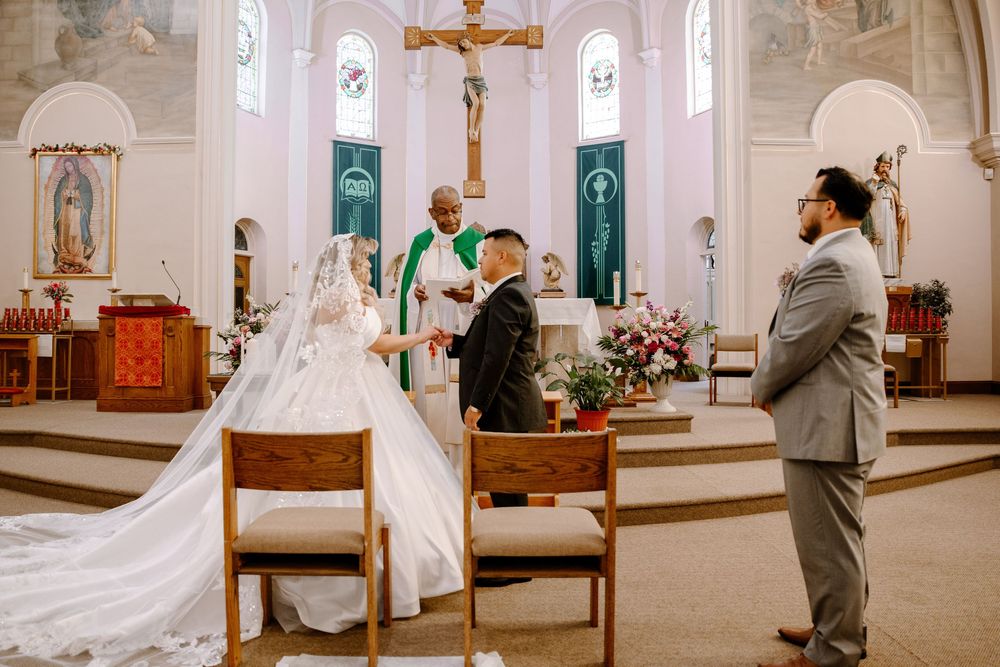 Wedding ceremony taking place inside a traditional church with white and gold architectural details.