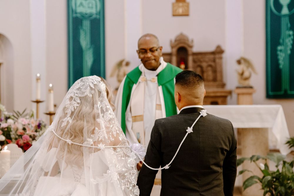 Religous ceremony taking place inside of an elegant church with green and white decor elements.