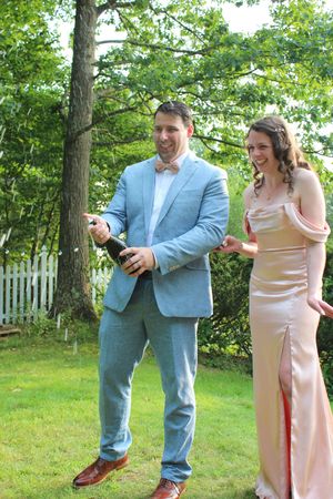 Candid photo of married couple uncorking champagne during wedding photo session.