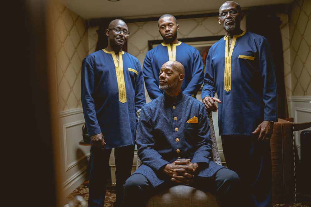A musical quartet dressed in coordinated blue and yellow formal attire pose in a hallway setting. Wedding at Westbury Manor