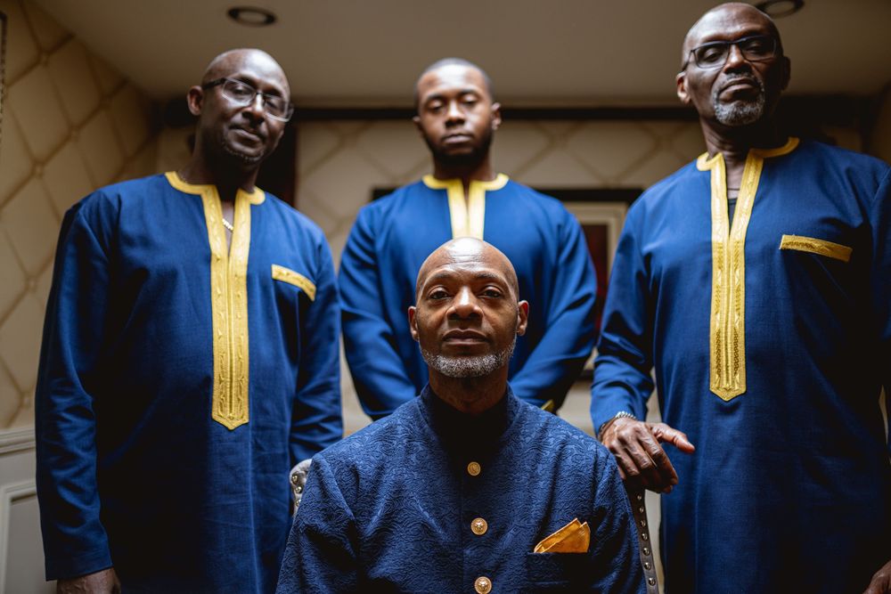 A group wearing matching blue and gold ceremonial performance uniforms pose together. Wedding at Westbury Manor