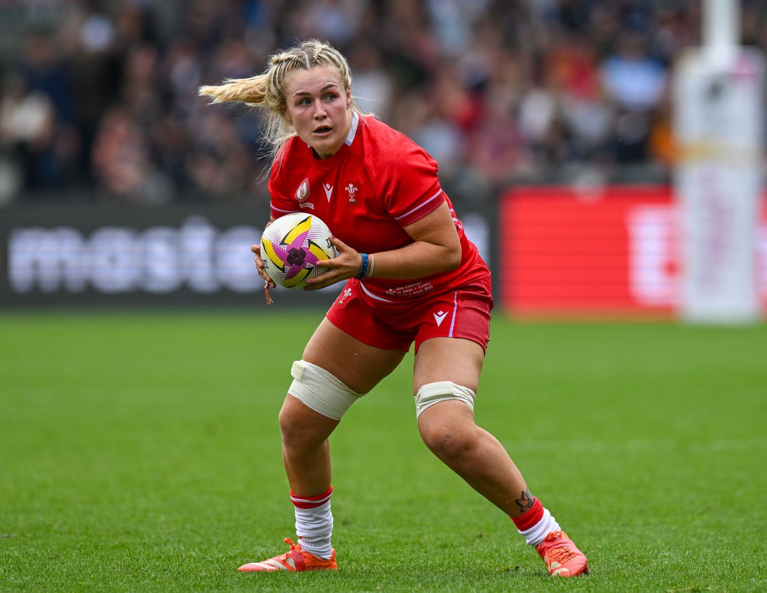 A rugby player runs with the ball during an intense match on a grass field.