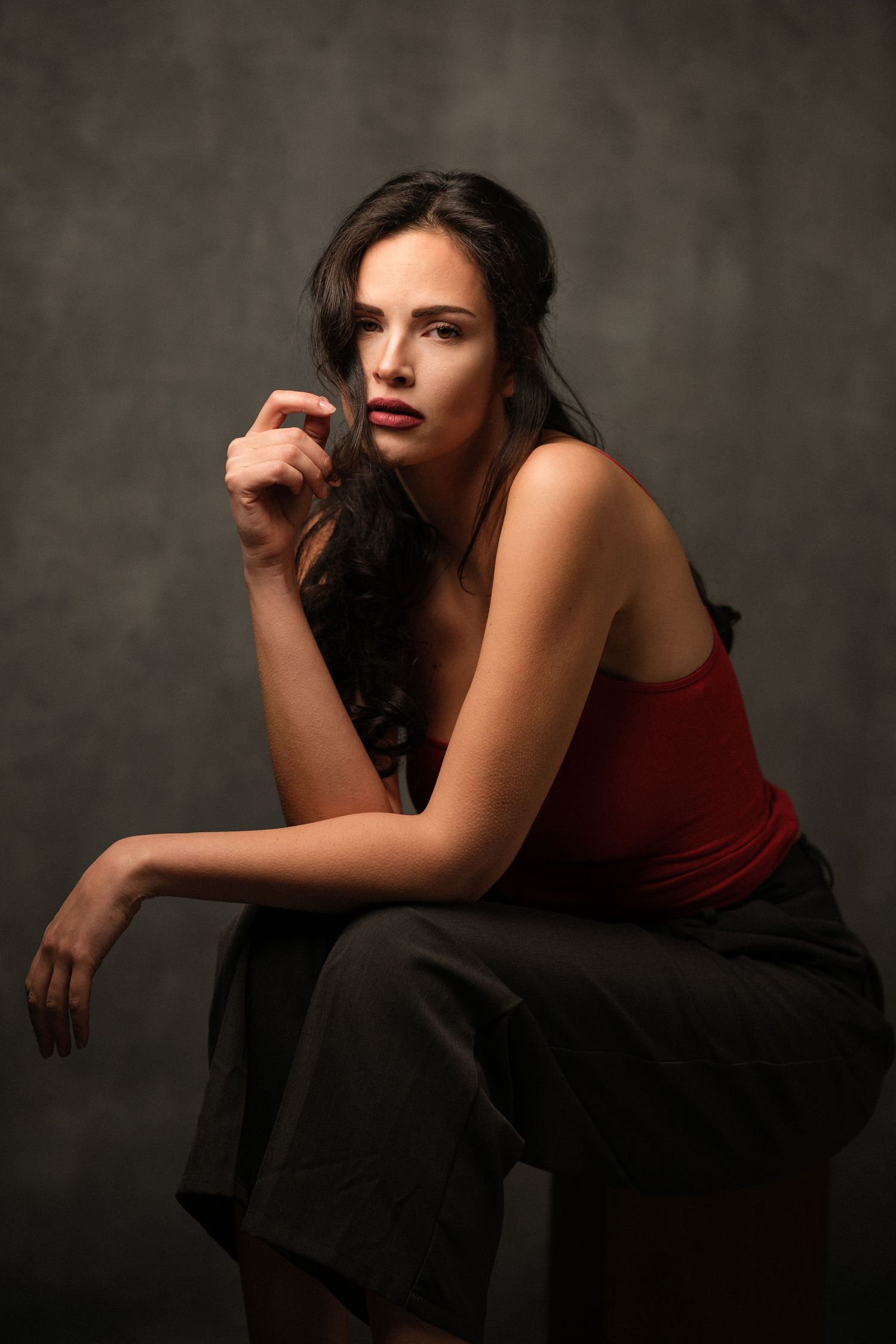 Dramatic portrait series of person in burgundy top against dark background.