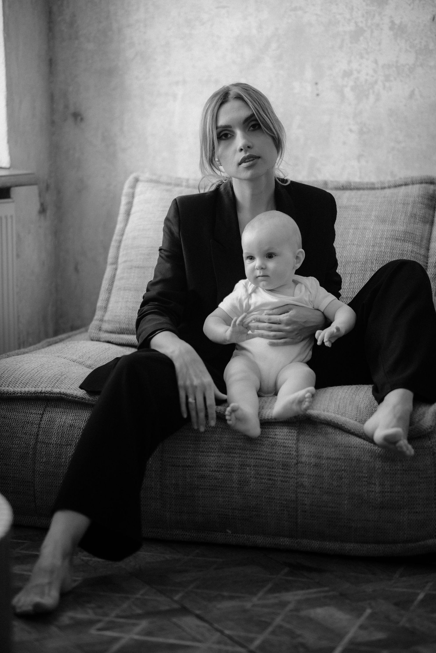 A sequence of black and white photos showing parent and infant sitting together on a couch.