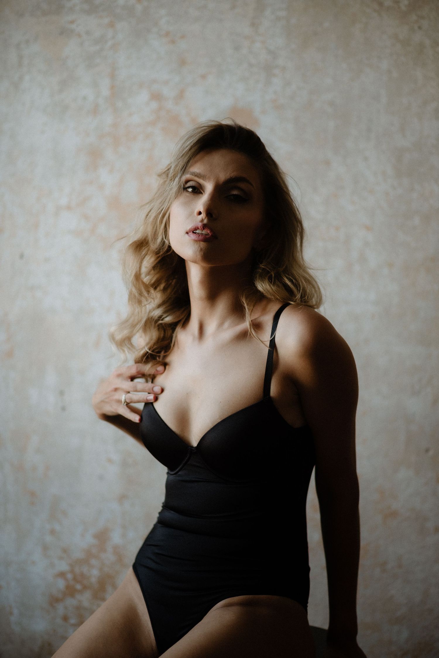Dynamic portrait series of a woman in black dress against textured wall creating dramatic mood and shadows.