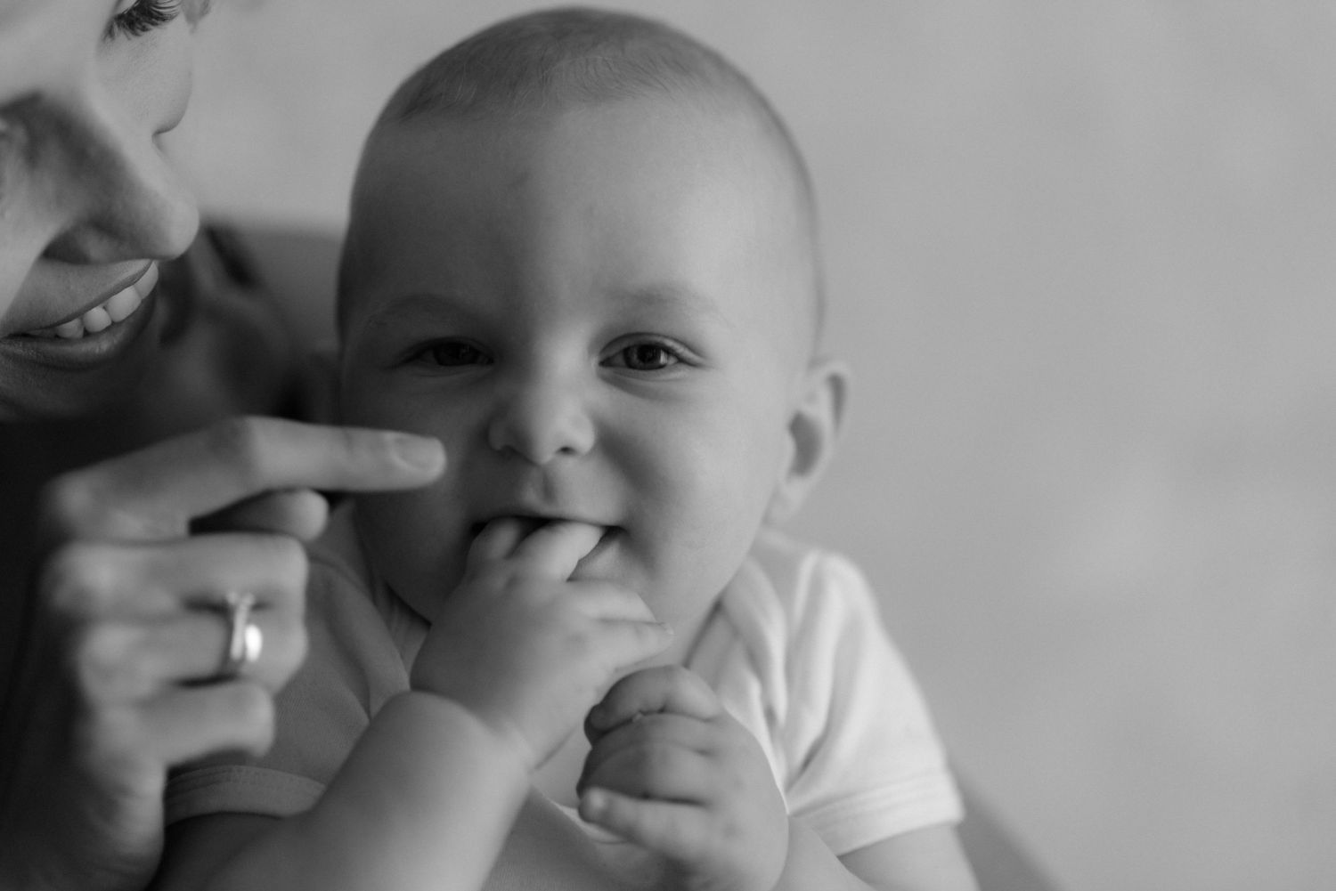 A series of black and white photos show a small baby making different facial expressions and playful gestures.