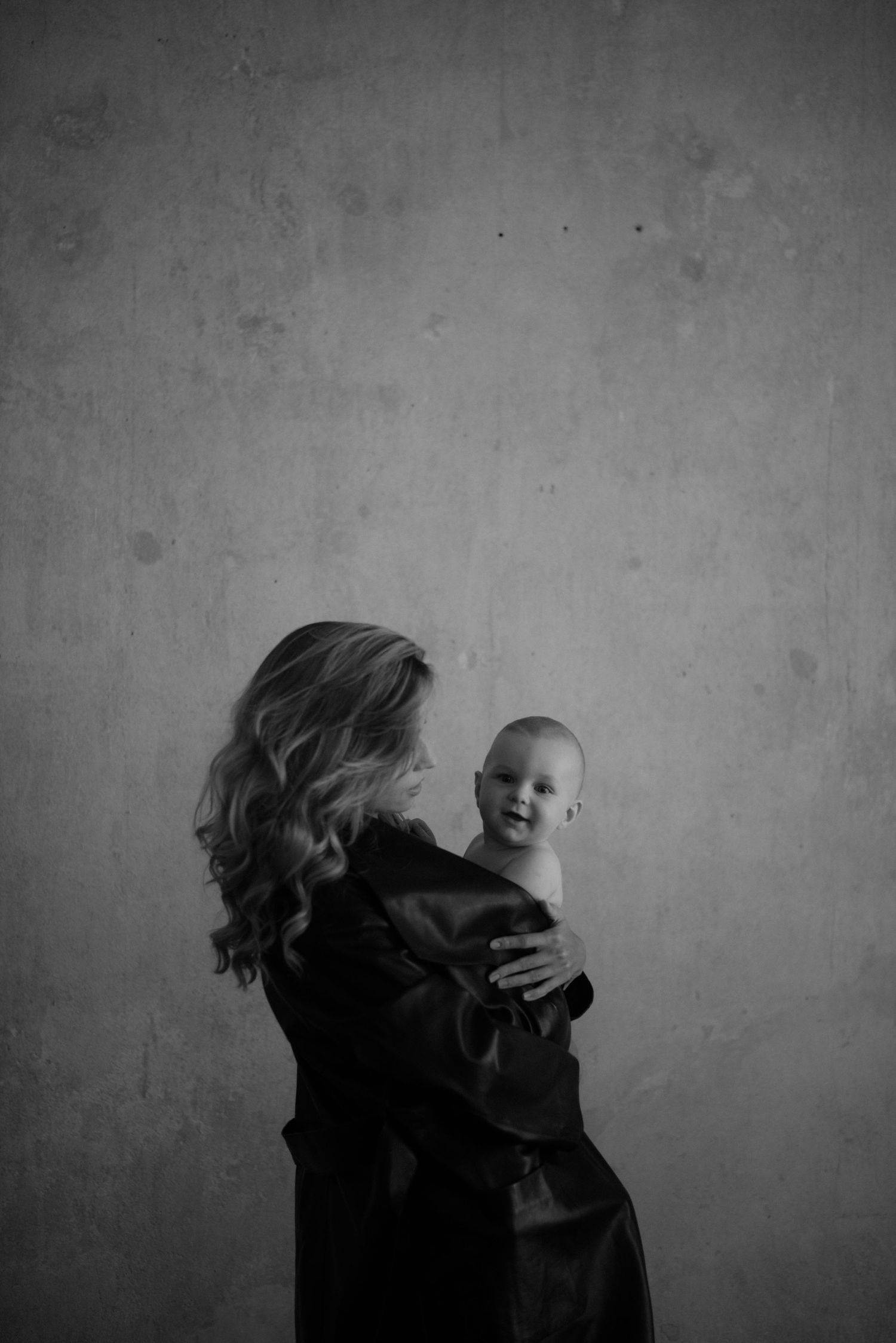 Moody black and white photo series capturing movement and interaction between adult and baby in dim lighting.