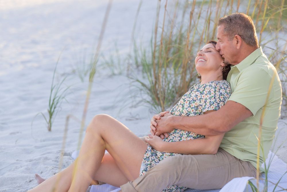 Couple relaxing together on a sandy beach near the water during a sunny afternoon.