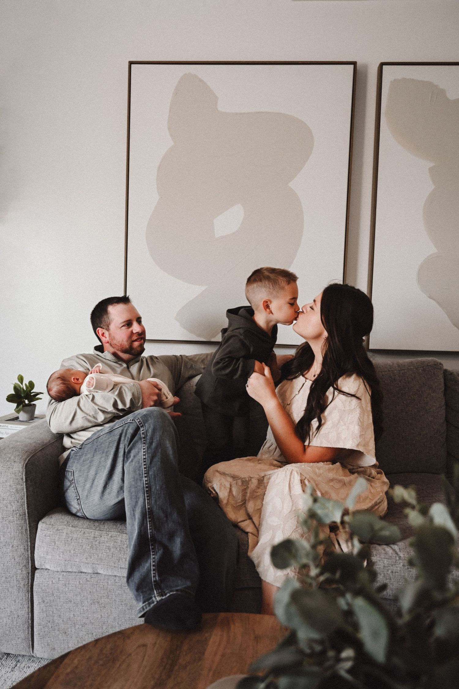 Couple lounging and playing on grey couch with wall art in background.