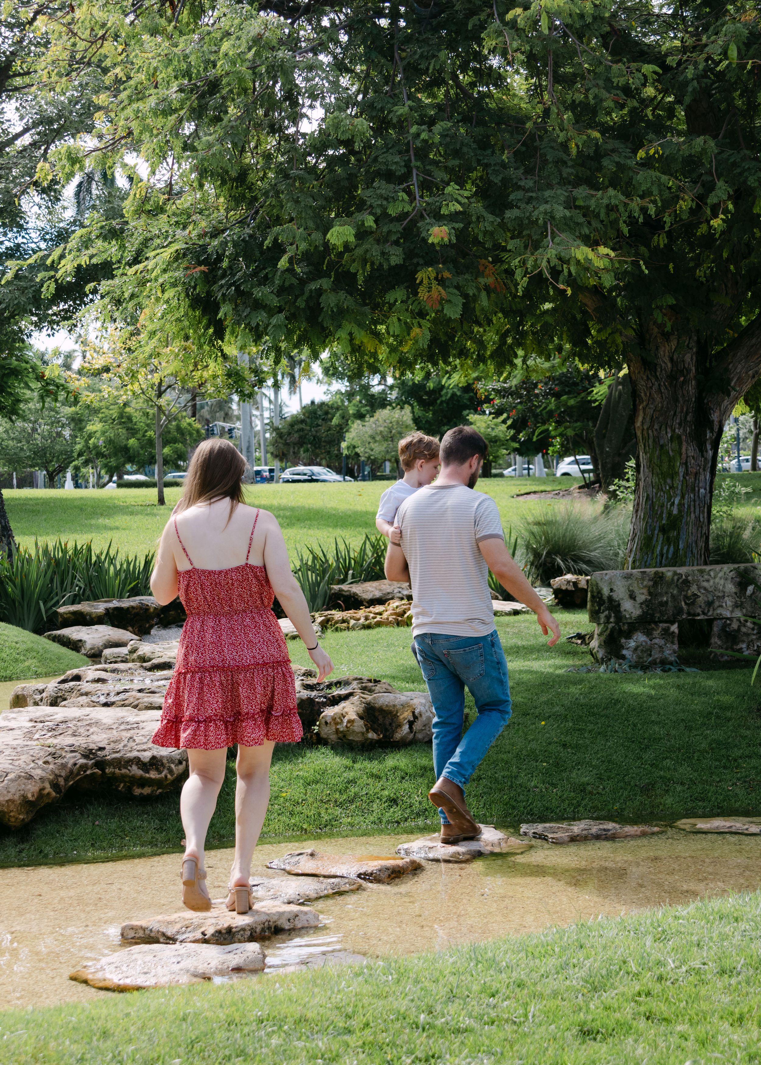 Family exploring stone path through green parkland on sunny day.