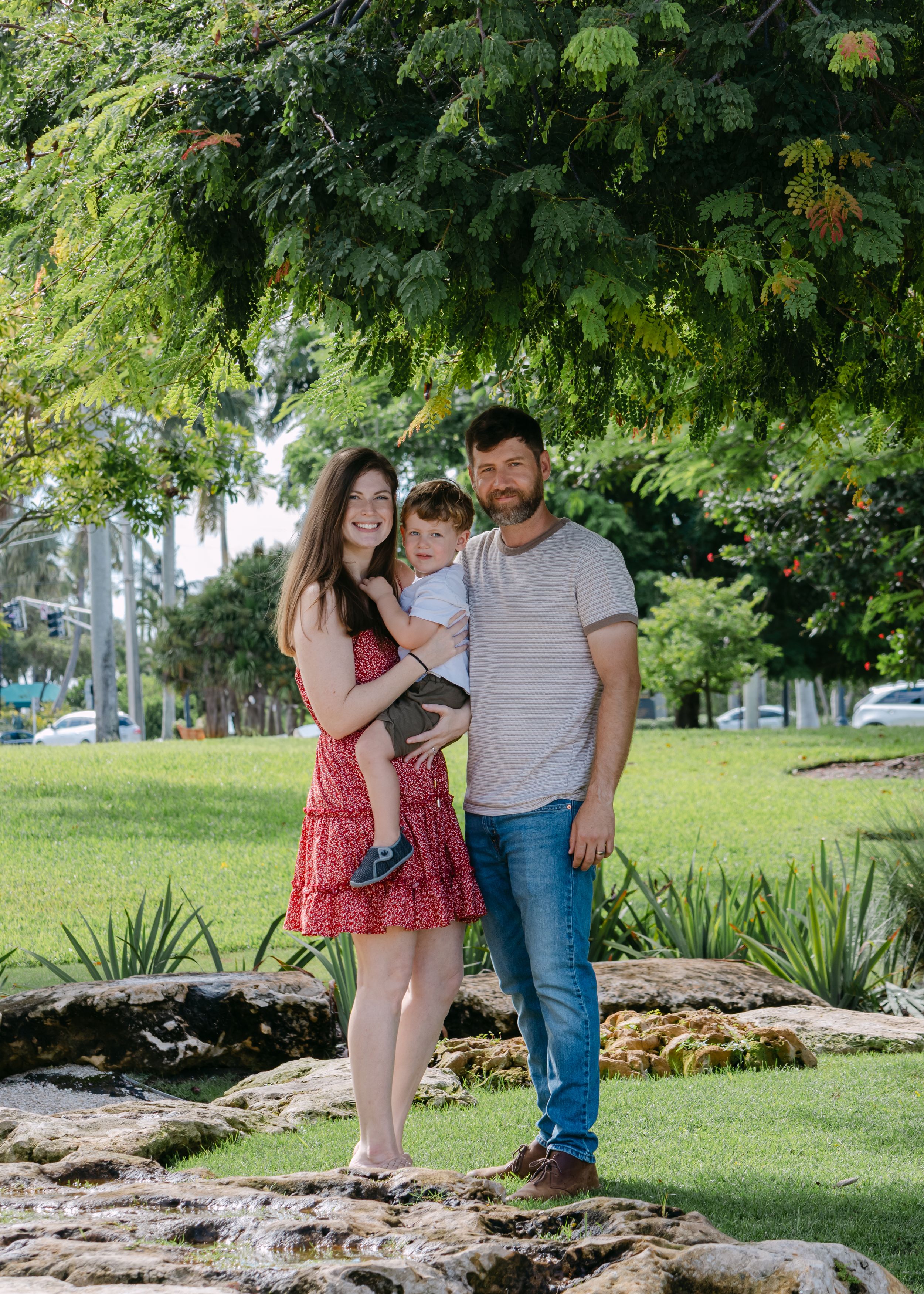 Family walking together on stone pathway in lush green park setting.