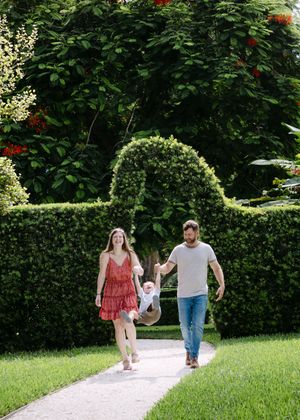 Three people stroll down a winding path in a scenic garden setting.