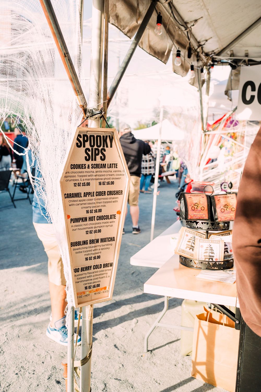 Brown paper bags with menu prices displayed at an outdoor event or market setting.