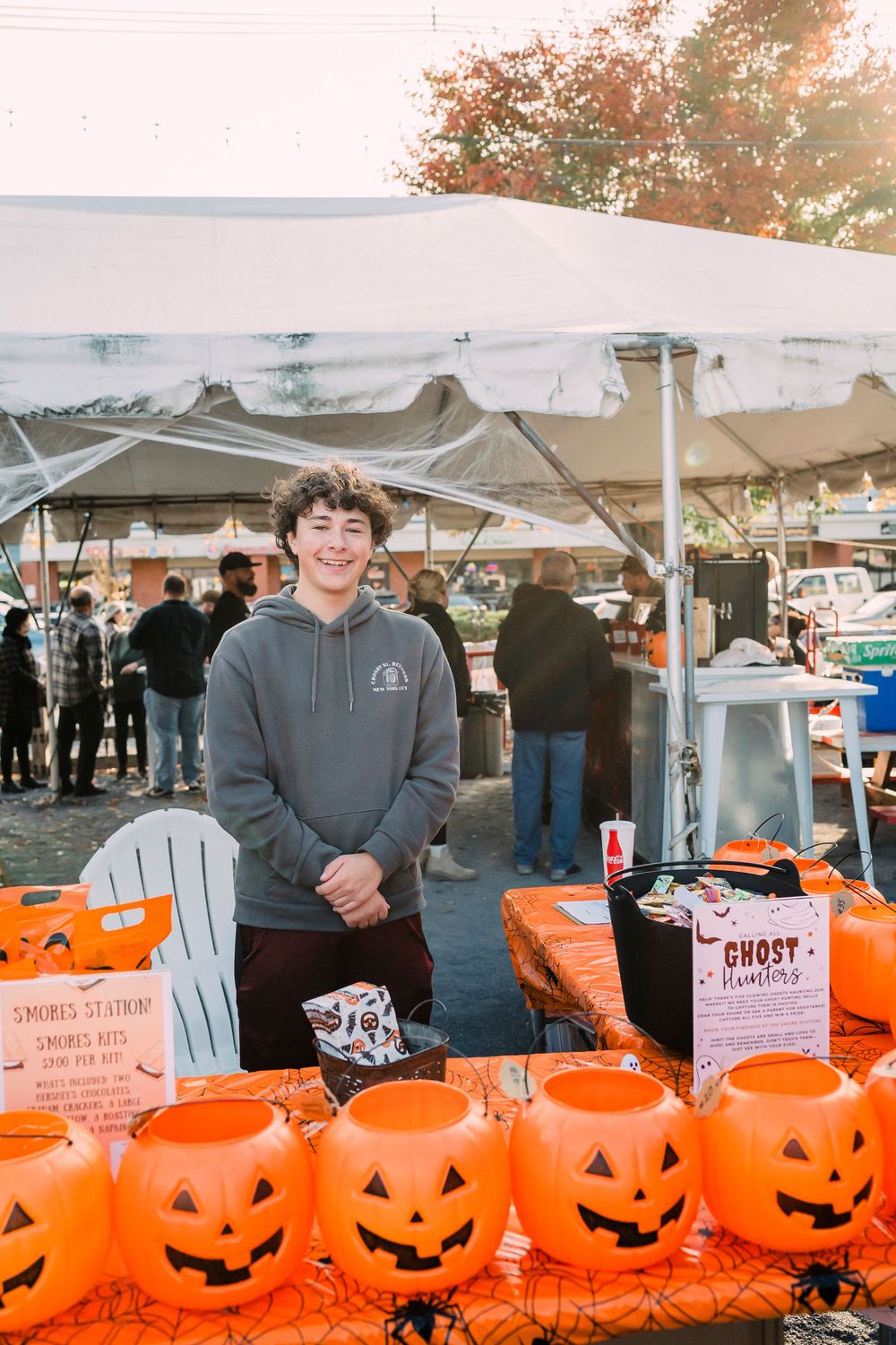 Row of bright orange plastic jack-o'-lantern buckets lined up at an outdoor market or festival display.