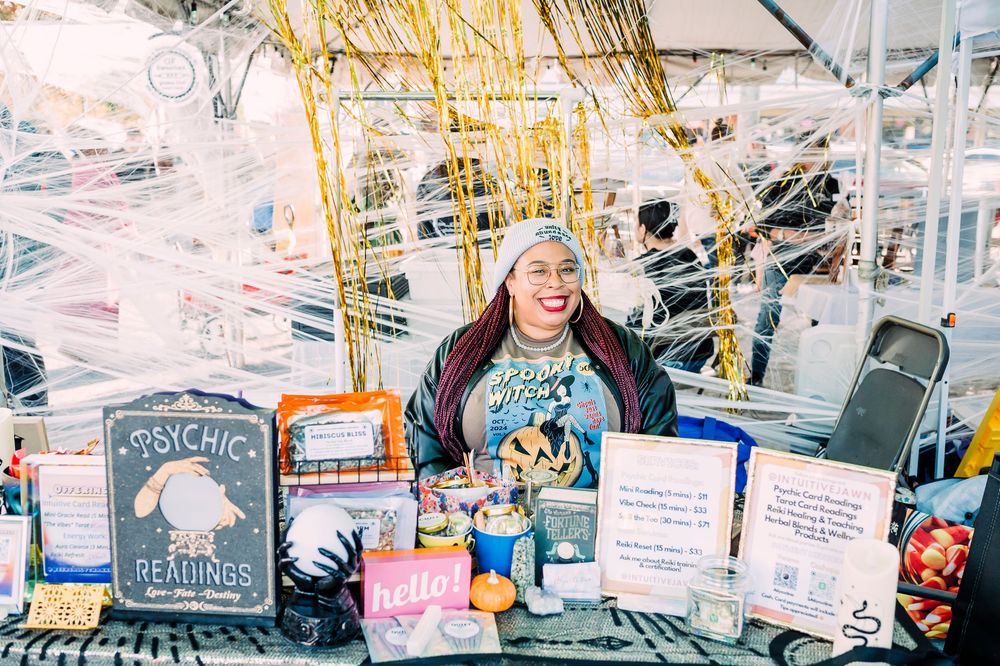 Person stands in front of a colorful ice cream shop counter displaying dessert flavors and toppings.