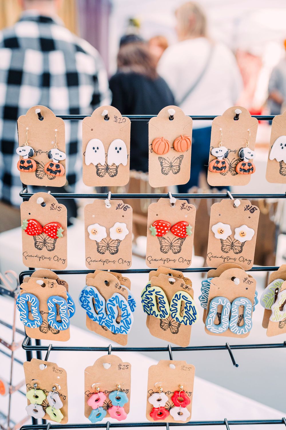 Rows of butterfly earrings displayed on kraft paper tags featuring various colors and designs.