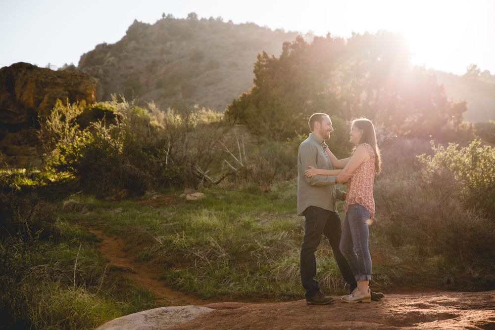 People walk along a sunlit path during golden hour in a scenic outdoor setting while the sun creates a warm glow.