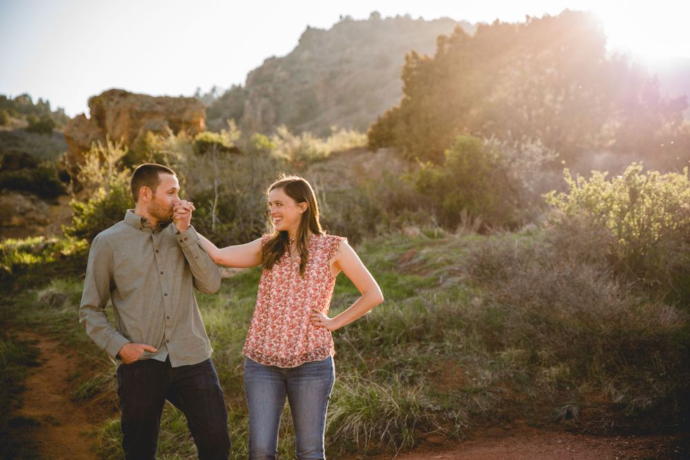 Golden sunlight illuminates a couple walking along a desert mountain trail on a beautiful evening.