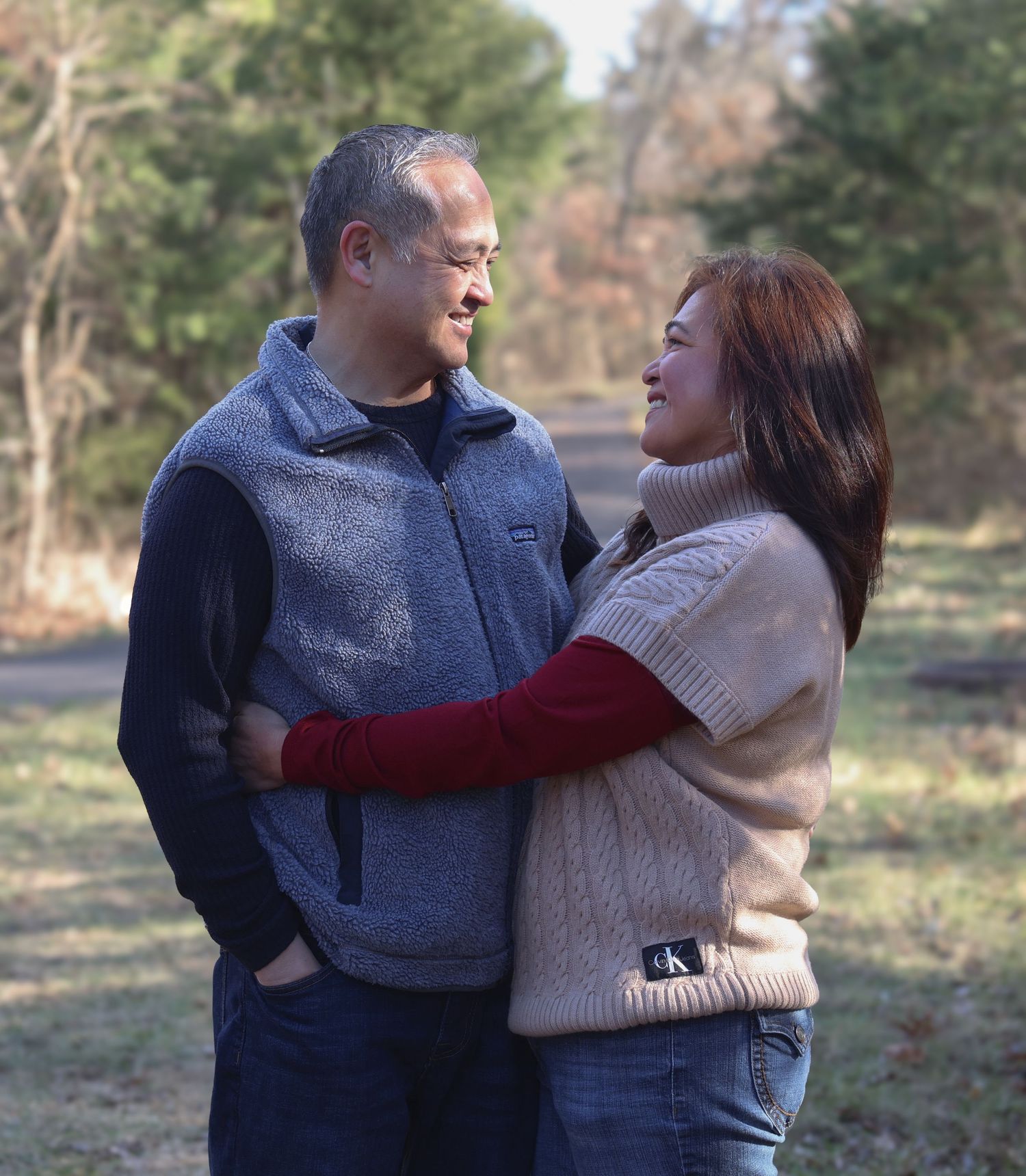 Two people share a tender moment embracing outdoors while wearing cozy sweaters on a winter day in nature.