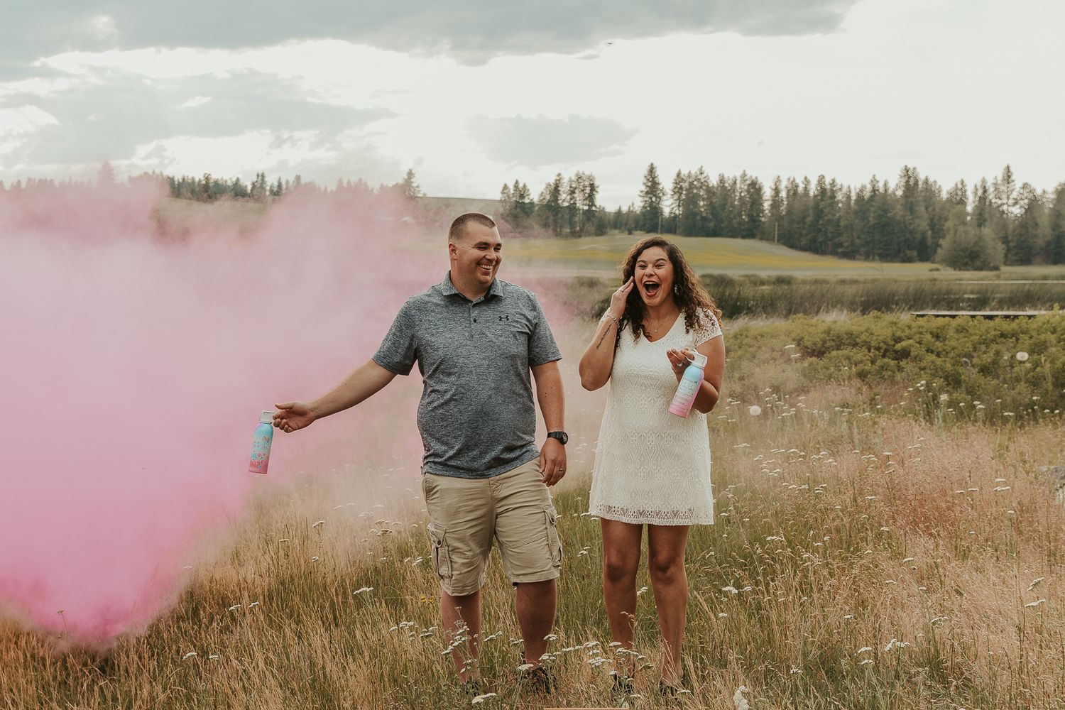 Celebrating gender reveal with pink powder smoke bombs in open field at outdoor photography venue in Spokane, Spokane family photographer